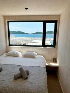 ein Schlafzimmer mit zwei Betten und einem großen Fenster in der Unterkunft BEACHHOUSE #1 - Buqez Resort in Drage