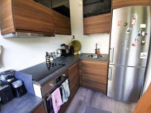 uma cozinha com um frigorífico de aço inoxidável e armários de madeira em Comfy boho-studio in Kallio. em Helsinque
