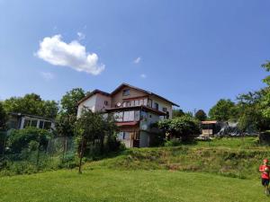 una mujer parada frente a una casa en una colina en Къща за гости Слънце Борики, en Gabrovo