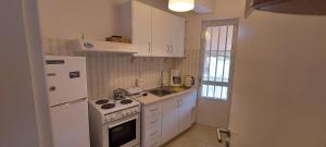 a white kitchen with a stove and a refrigerator at OIKIKA B10 in Artemida
