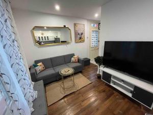 a living room with a couch and a large flat screen tv at K3- Maison 2min RER 15min PARIS-EXPO 4 chambres/10 lits in Bagneux