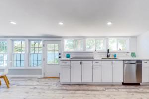 a white kitchen with white cabinets and windows at Magic on Micajah in Plymouth