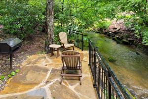 two chairs and a table on a railing next to a river at Down the Creek in Gatlinburg