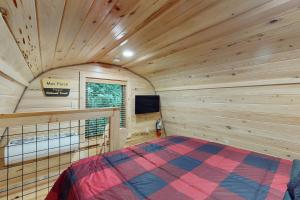 Blockhausschlafzimmer mit einem Bett und einem TV in der Unterkunft Down the Creek in Gatlinburg