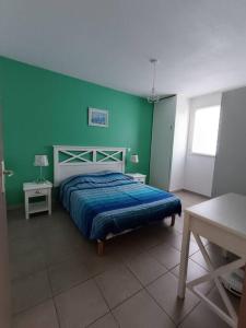1 dormitorio con cama y pared verde en L'argentière, proche plage,Résidence piscine, Tennis, parking en La Londe-les-Maures