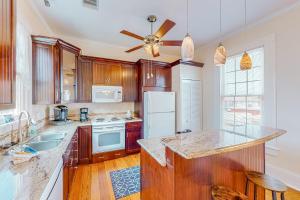- une cuisine avec des placards en bois et un réfrigérateur blanc dans l'établissement Coastal Breeze, à Galveston