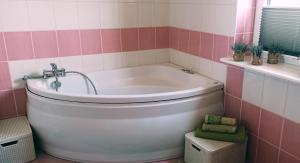 にあるRychtyńska Ciszaのピンクと白のタイルを使用したバスルーム(バスタブ付)