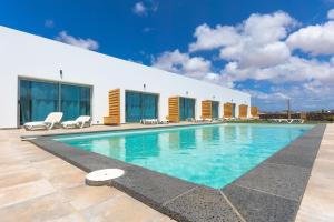 una piscina con sillas y un edificio en Lola Family Lajares iRent Fuerteventura, en La Oliva