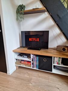 a living room with a tv on a entertainment center at Maison "Le Figuier" TREVOUX climatisée in Trévoux +15 photos