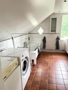 uma casa de banho com uma máquina de lavar e secar roupa num piso de azulejo em Charmig villa norr om Stockholm em Vallentuna