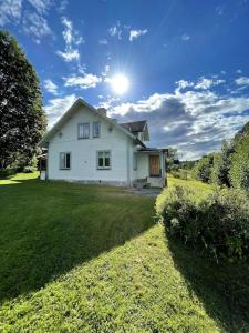 una casa blanca en un césped con el sol en el cielo en Charmig villa norr om Stockholm en Vallentuna