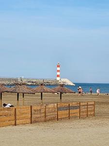 ein Strand mit Leuchtturm und Menschen am Strand in der Unterkunft Mobil-home tout confort in Sigean