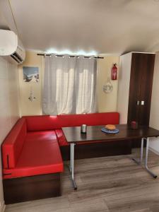 ein Wohnzimmer mit einem roten Sofa und einem Tisch in der Unterkunft Mobil-home tout confort in Sigean