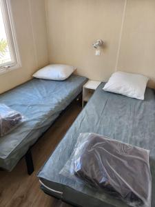 two beds in a small room with a window at Mobil-home tout confort in Sigean
