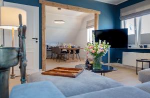 a living room with blue walls and a table with flowers at Backbord in Westerland