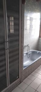 Corneguerre Grand Brassac في La Peyzie: حوض استحمام في الحمام مع باب زجاجي