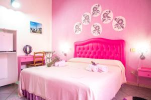 a pink bedroom with a bed with towels on it at Sa Pramma in Baratili San Pietro