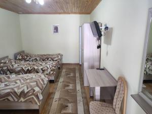 a room with two beds and a table and a tv at В Гостях на Иссык-Куле in Cholpon-Ata