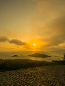 a sunset on the beach with the sun in the sky at Arraial Praia Ap - Residence Club Praia dos Anjos in Arraial do Cabo