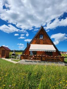 a large wooden barn with a field of flowers at ROMANIJA - Brvnara za odmor in Han Pijesak