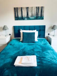 a bedroom with a blue bed with a blue blanket at Beechwood Accommodation in North Leeds in Leeds