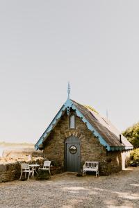 ein kleines Backsteingebäude mit zwei Stühlen und einer Bank in der Unterkunft The Boathouse at Old Court in Strangford