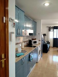 uma cozinha com armários azuis e uma sala de estar em Apto Puipana em Corralejo
