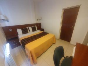 a bedroom with a bed and a chair in it at Hotel Pueblo Huarpe in San Luis