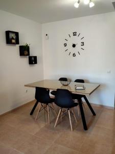 uma mesa de jantar com cadeiras e um relógio na parede em Apto Puipana em Corralejo