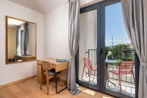 a room with a desk and a balcony with chairs at PERUNIKA BED & BREAKFAST in Mošćenička Draga