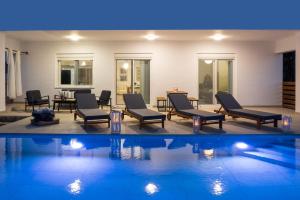 a swimming pool with chairs and a table and a swimming pool at Aelia Luxury Villa in Sálakos