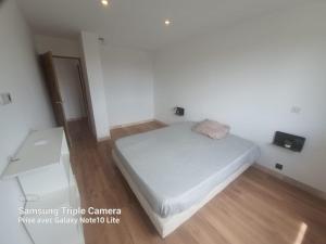 ein kleines Schlafzimmer mit einem weißen Bett und einem Holzboden in der Unterkunft Appartement Climatisé in Fréjus
