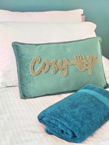 a pillow with the word cozy written on it on a bed at Parkside 2 bedrooms appartment with encolsed garden in Largs
