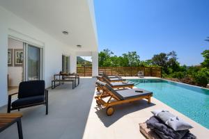 a patio with lounge chairs and a swimming pool at Aelia Luxury Villa in Sálakos