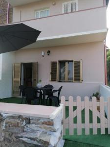 a house with a white fence and chairs and an umbrella at La casetta di Tzia Caicca in Iglesias