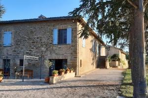 un edificio in pietra con finestre blu e piante all'interno di esso di Ca' Gulino - Urbino - Villa con Minipiscina in Borgo Antico a Urbino