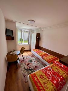 ein Hotelzimmer mit 2 Betten, einem Tisch und einem Fenster in der Unterkunft Privat Agnesa in Zuberec