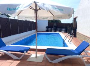 an umbrella and chairs next to a swimming pool at Casa independiente con piscina - Villa Pintor in Conil de la Frontera