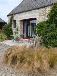 una casa in pietra con tavolo e panca all'esterno di La ferme de Lec'h Hameury a Plestin-les-Grèves