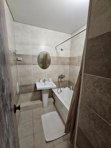 a bathroom with a sink and a tub and a mirror at Apartment on Constantin Negruzzi in Chişinău