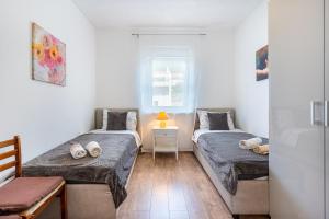 um quarto com 2 camas e uma mesa com um candeeiro em Apartments Tatjana II em Cres