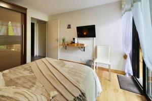 sypialnia z łóżkiem i telewizorem na ścianie w obiekcie Chambres et Table d'hotes du calvaire w mieście Villefranche-de-Rouergue
