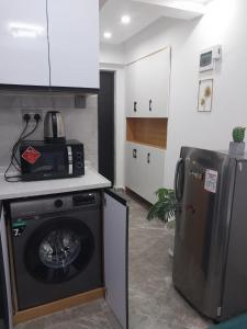 a kitchen with a washing machine and a refrigerator at Heartland Gardens Apartments Kilimani Nairobi in Nairobi