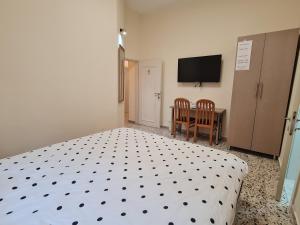 a bedroom with a bed and a table and a television at Rizik's Guest House in Nazareth