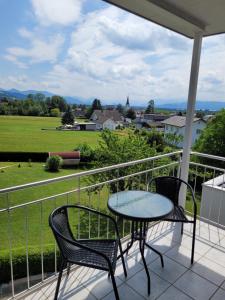 a table and chairs on a balcony with a view of a field at Gästezimmer Suppan in Hörbranz