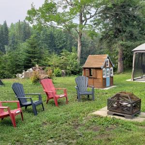 a group of chairs and a play house in the yard at Le Chalet Amical in Saint-Paulin