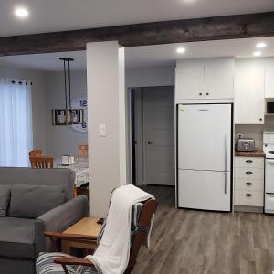 ein Wohnzimmer mit einem Sofa und einem weißen Kühlschrank in der Unterkunft Le Chalet Amical in Saint-Paulin