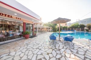 a patio with chairs and an umbrella next to a pool at Kalias Hotel in Vasiliki