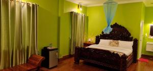 ein Schlafzimmer mit grünen Wänden, einem Bett und einem Stuhl in der Unterkunft Toek Chha Temple Resort in Kampong Cham
