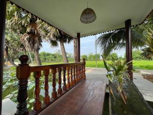 a porch with a wooden bench and palm trees at Toek Chha Temple Resort in Kampong Cham